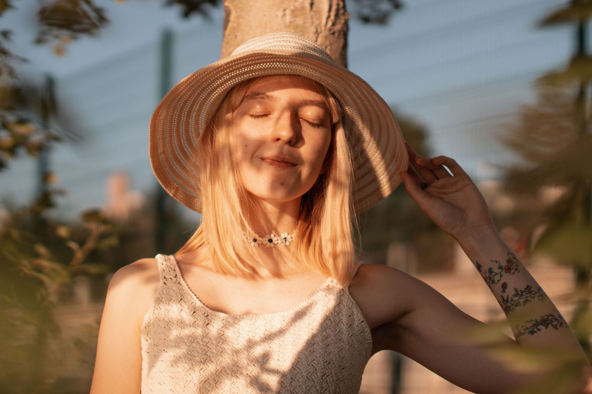 Tranquil portrait of a woman wearing a sun hat, enjoying a sunny day outdoors