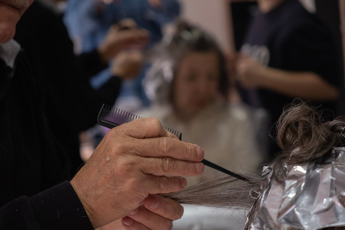 Hair salon scene with a hairdresser using foil and comb for highlights