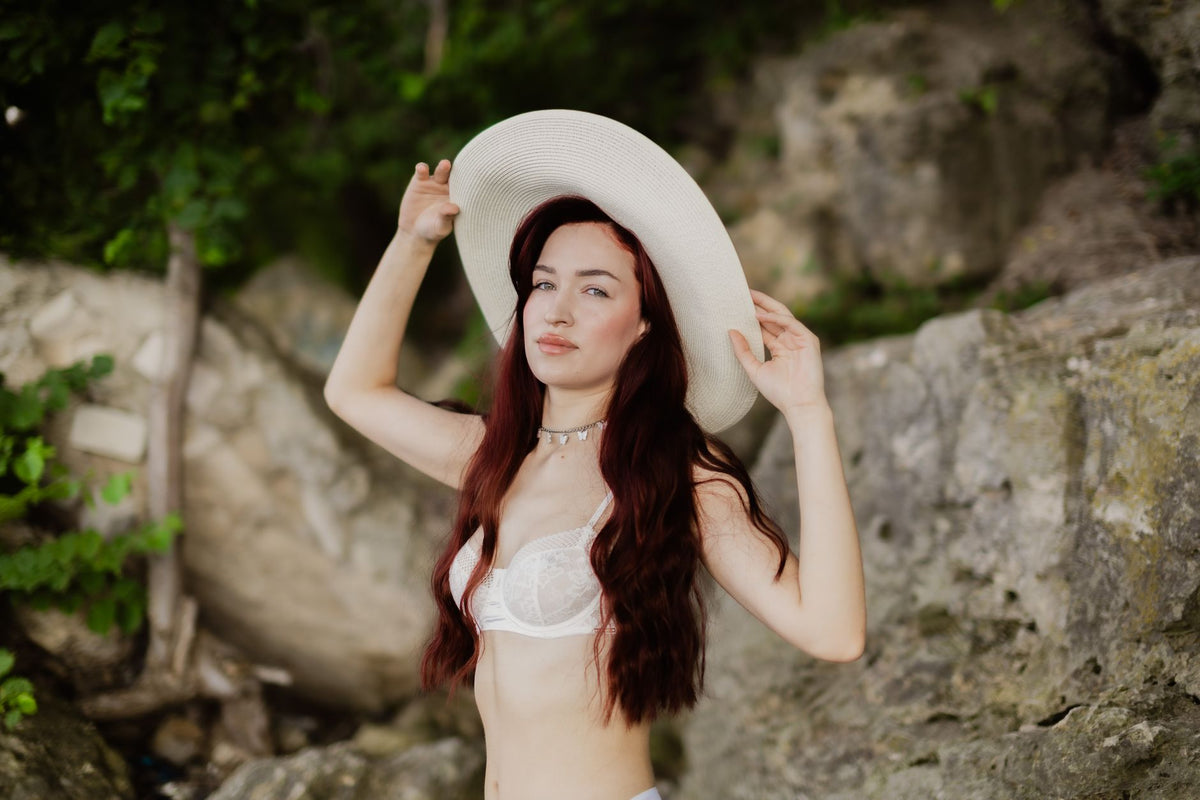 A young woman with red hair wearing a sun hat enjoys a summer day outdoors
