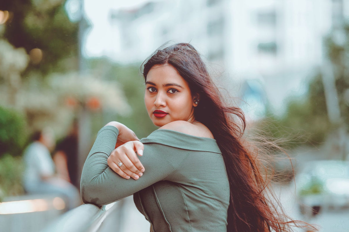 Woman with long hair posing outdoors, wearing green top