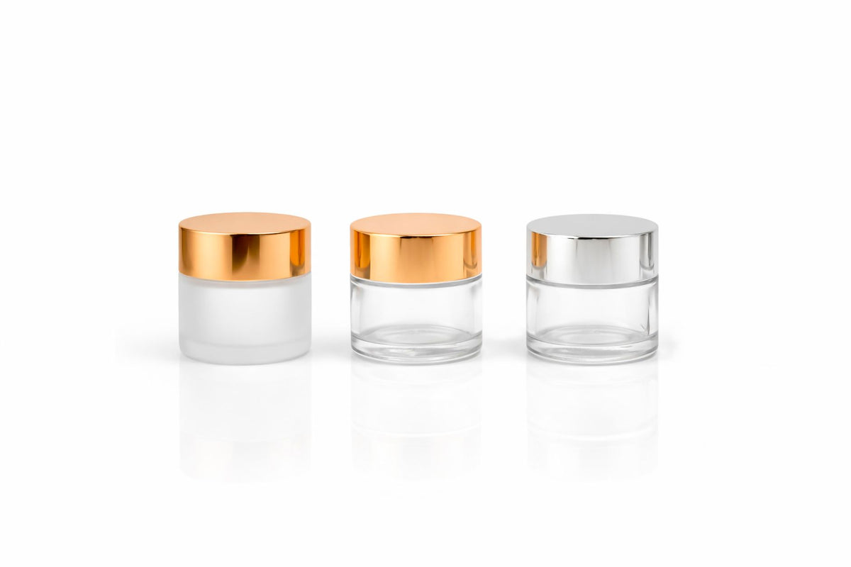 Stylish glass cosmetic jars with metallic lids on a white background, perfect for beauty packaging concepts