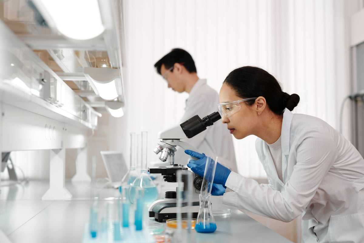 Two scientists in a lab examining samples with a microscope. Focus on scientific research and discovery
