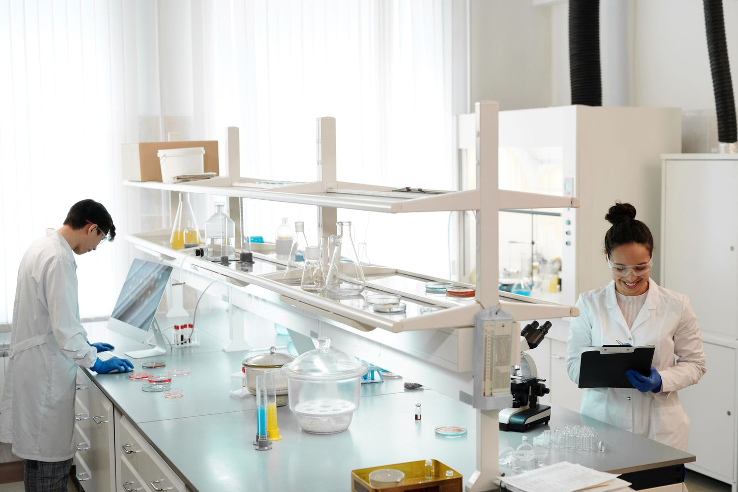 Two scientists working in a modern laboratory setting, analyzing and documenting experiments