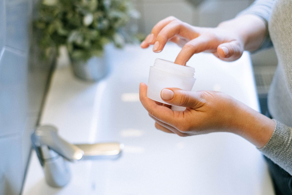 Close-up of woman's hands applying face cream, emphasizing self-care routine
