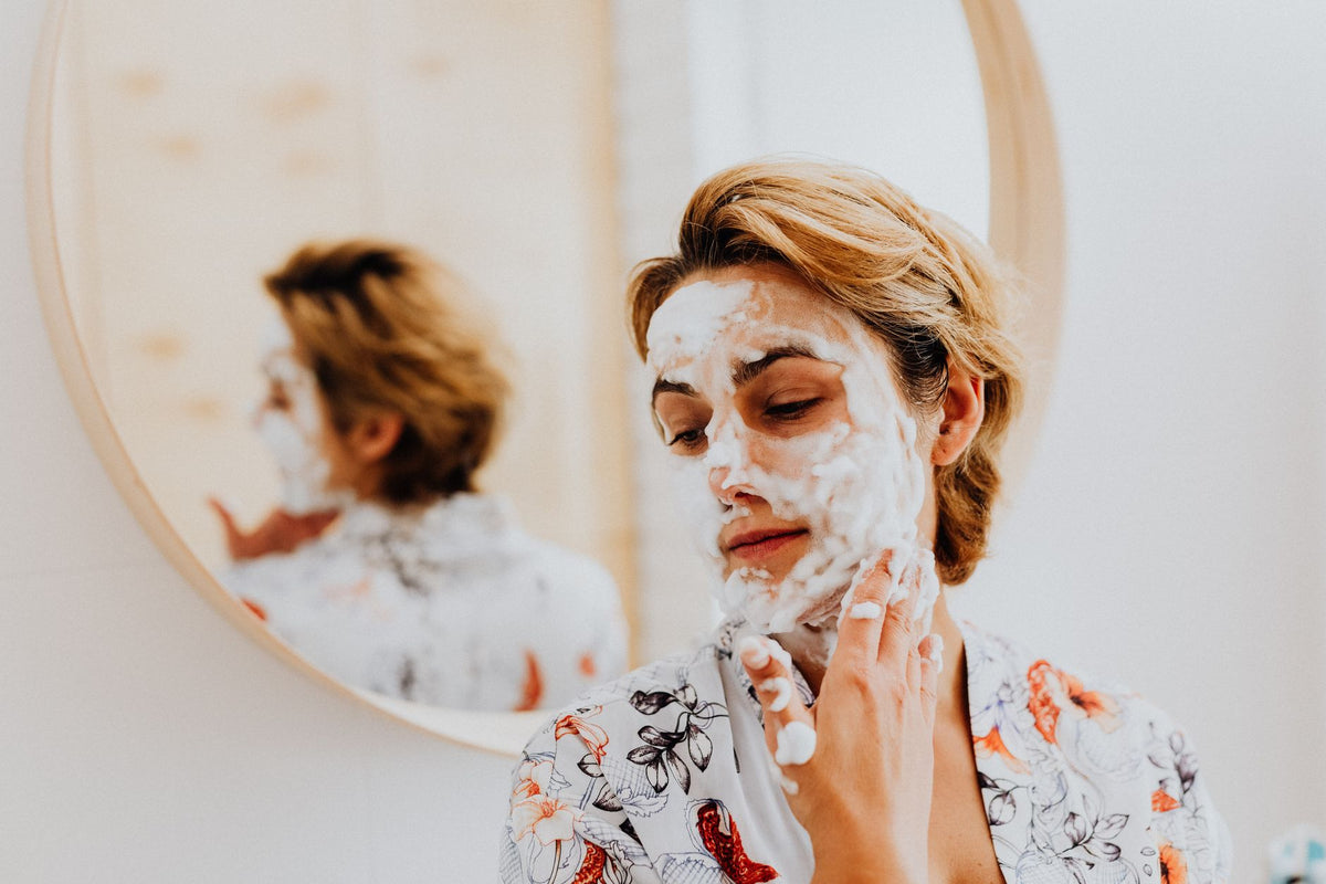 A woman enjoying a relaxing skincare routine with a facial mask in her bathroom, reflecting personal care