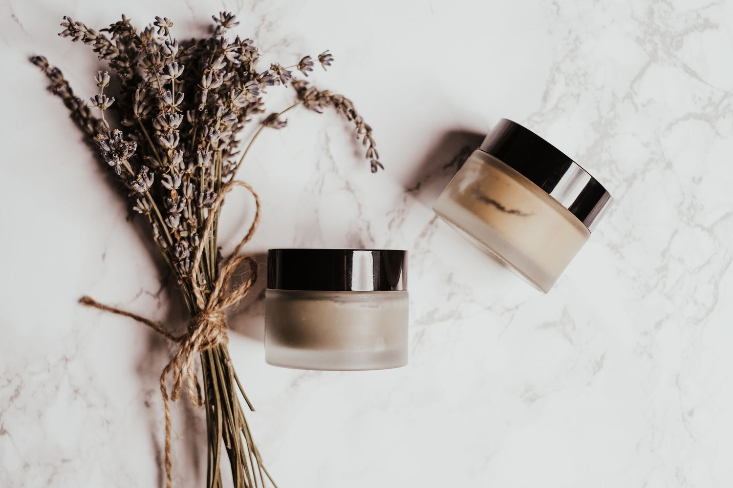 Skincare jars and lavender arranged on a marble surface, perfect for beauty and wellness themes