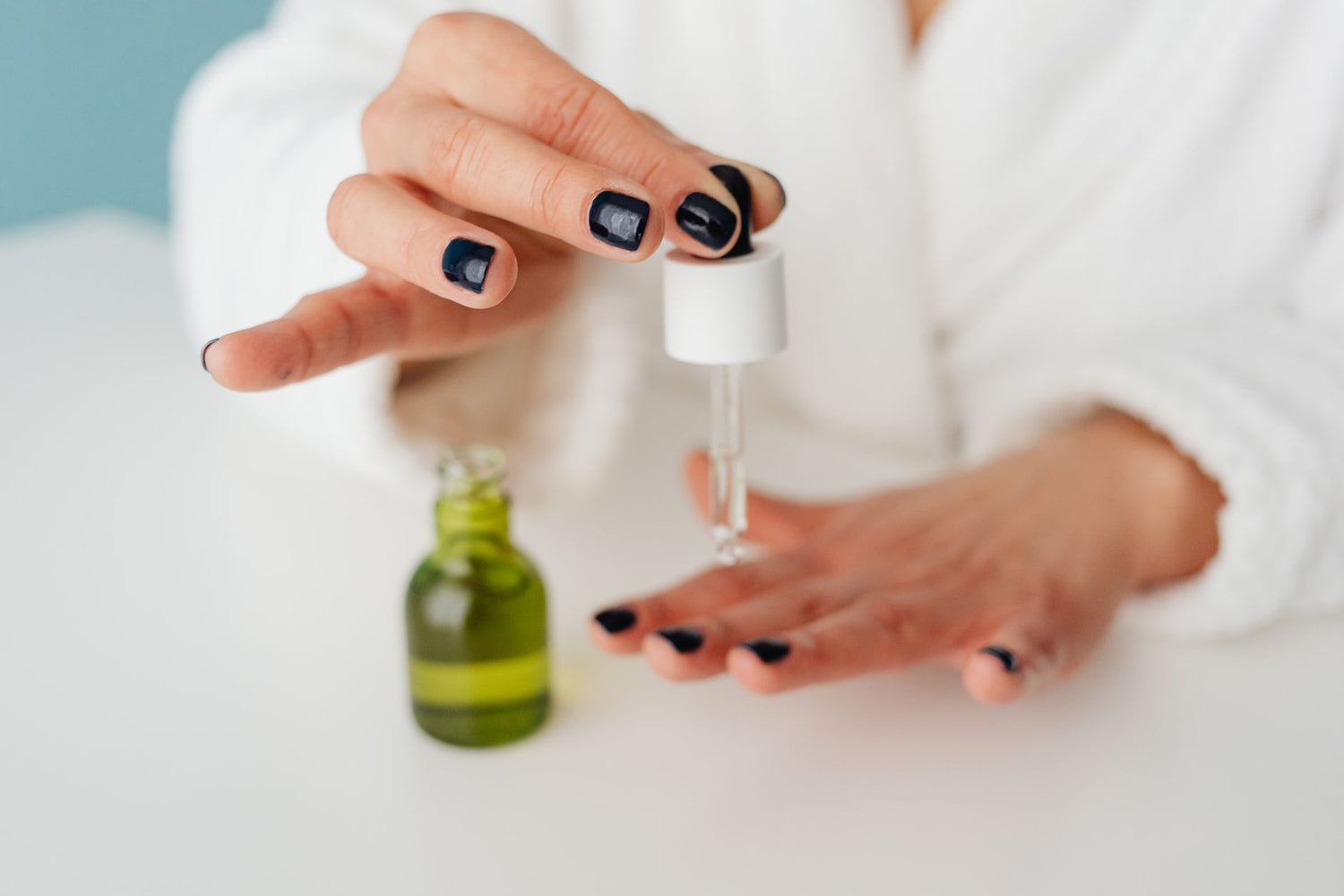 Close-up of a woman applying skincare serum with a dropper to her hand