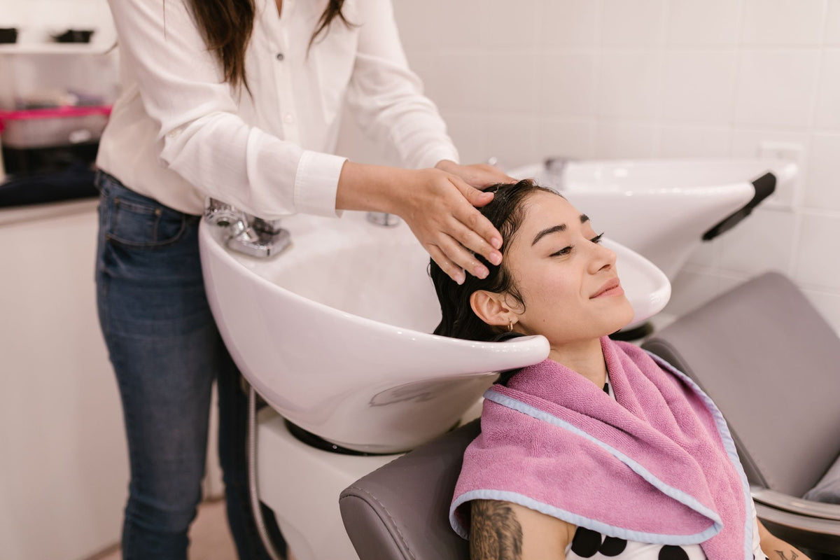 A woman enjoys a relaxing hair wash at a modern salon, symbolizing self-care and pampering