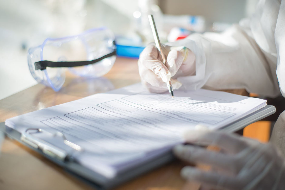 Close-up of a scientist writing on a document with gloved hands in a laboratory setting