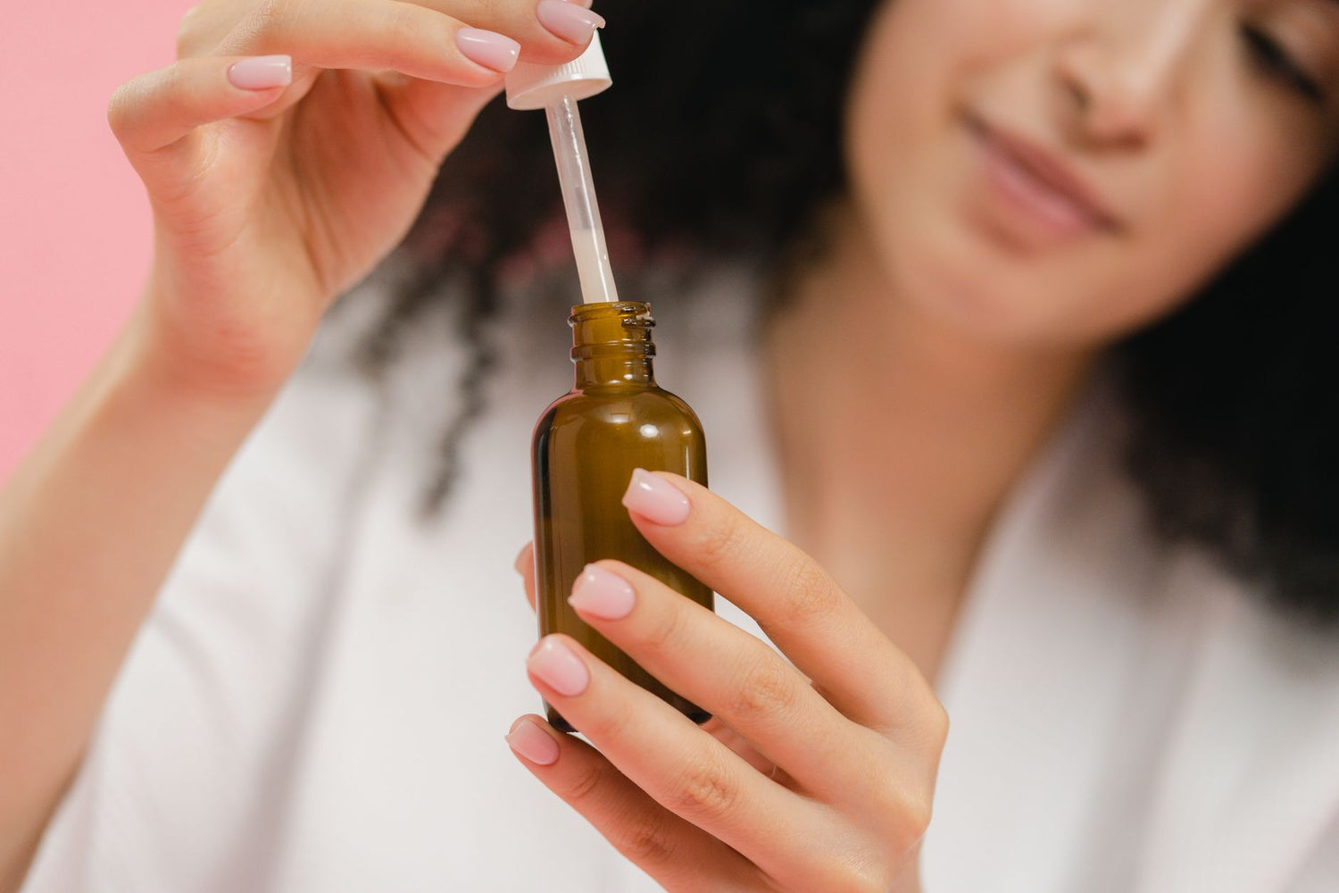 Close-up of a woman using a dropper bottle, focusing on skincare and beauty routine