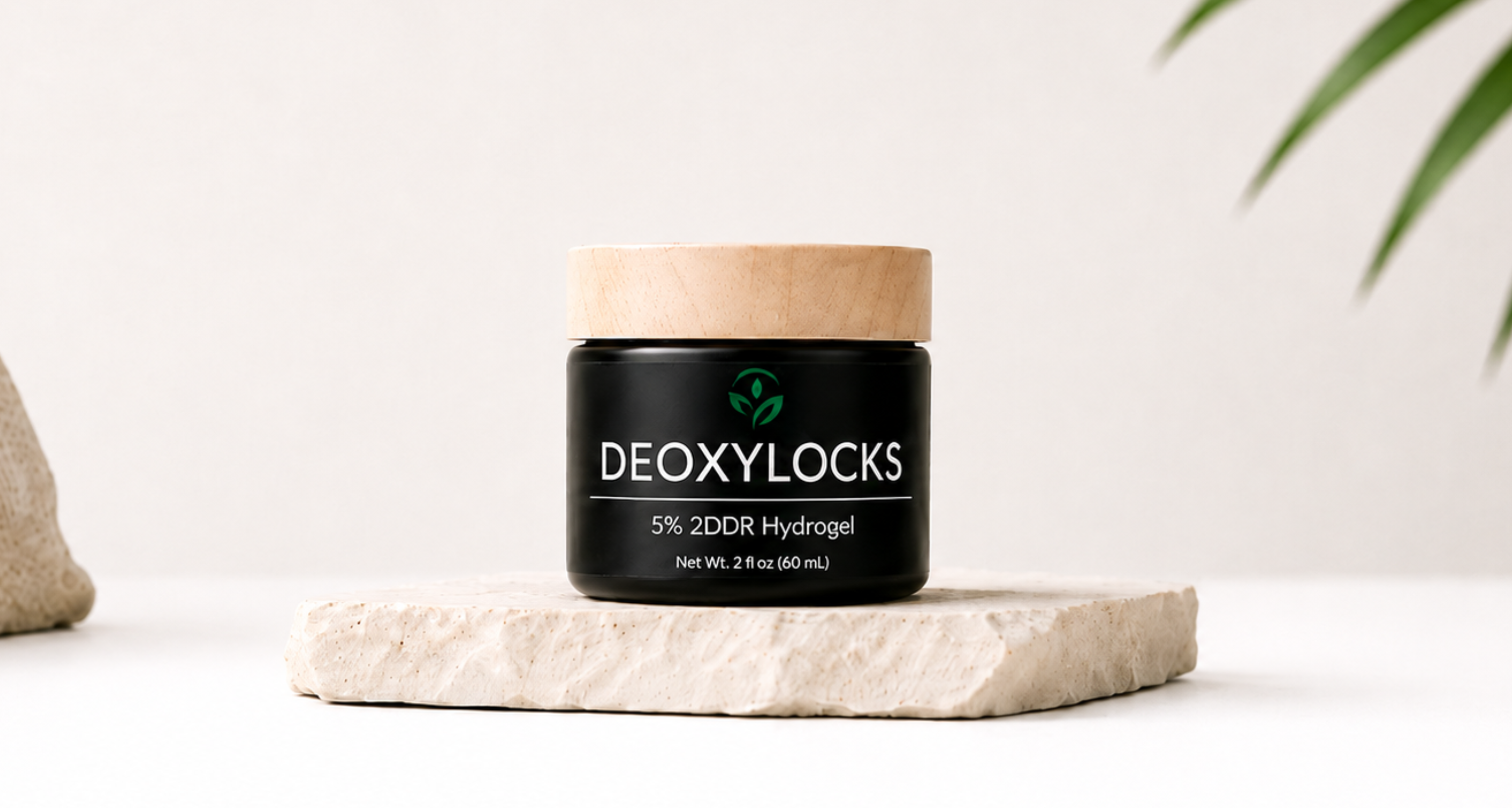 A black jar of DEOXYLOCKS 5% 2DDR Hydrogel with a light wood lid, displayed on a textured stone slab against a clean white background.