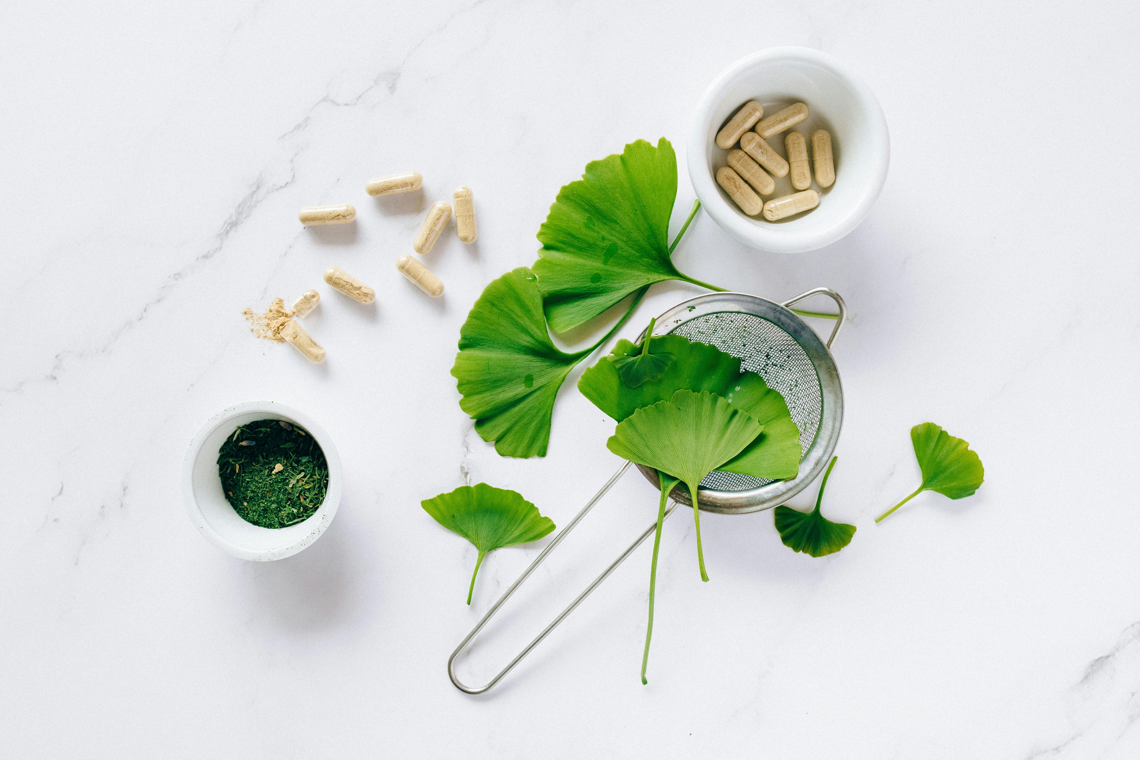 Natural ingredients including ginkgo biloba leaves, herbal capsules, and green powder – symbolizing the clean, botanical science behind Deoxylocks 2DDR Hydrogel