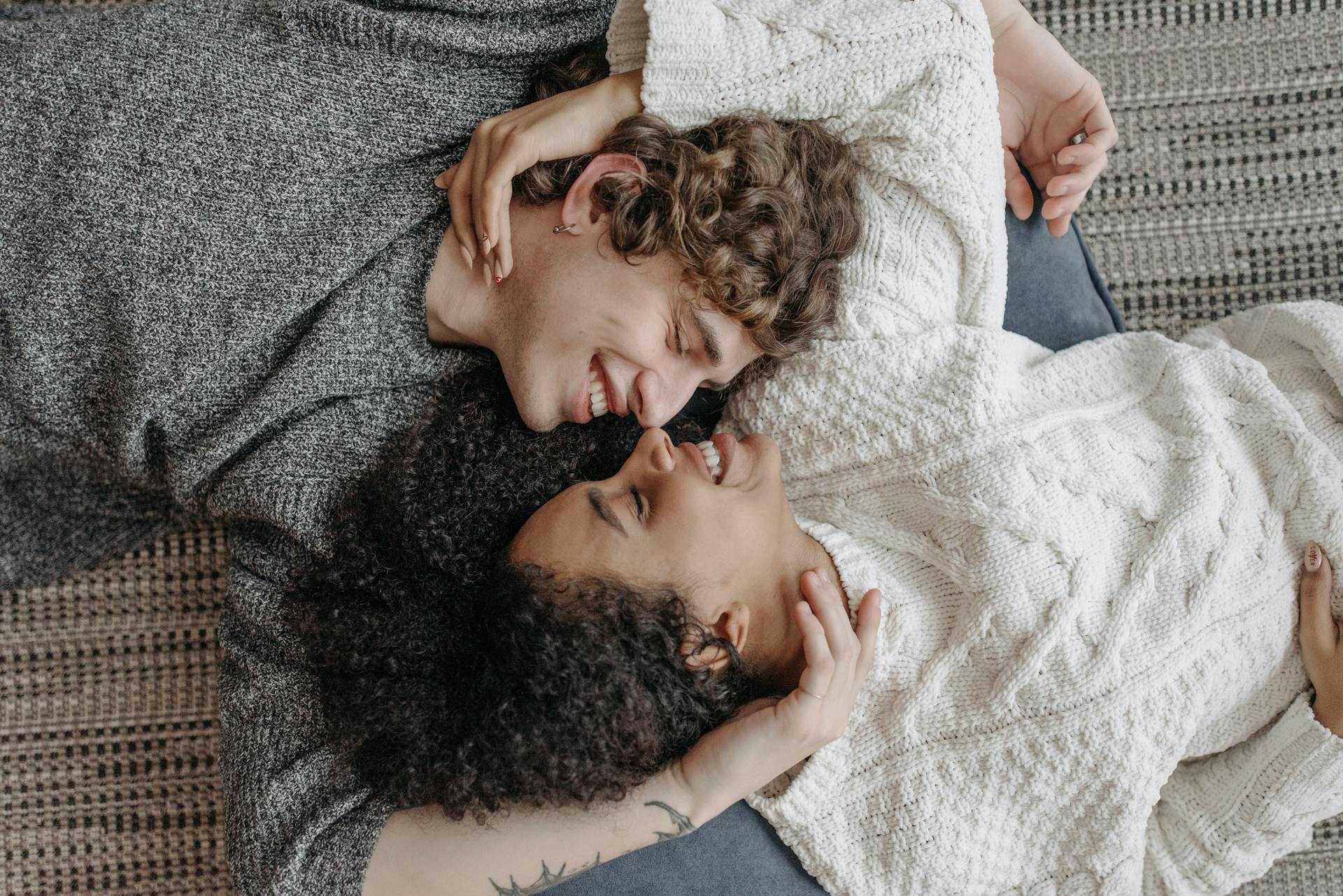 Two people lying on a bed, embracing each other.